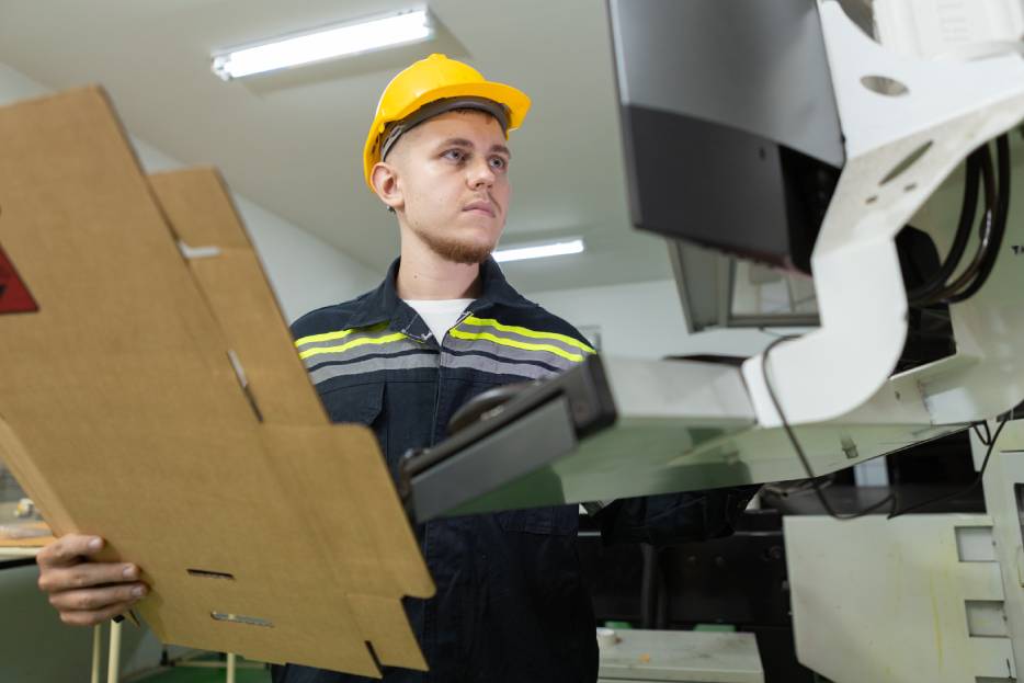 Empleado de una fábrica de cajas de cartón aplica un diagnóstico rápido a la máquina para evitar fallas